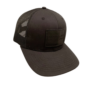 Revivalist Design hat. Black trucker hat with black leather patch embossed with "REVIVALIST design." Hat worn by woodworkers and interior designers, its a minimalist hat design that is simple and elegant.