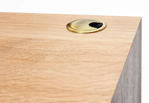 detailed picture of the white oak wood grain on the custom designed cascade desk. Shows the detail of the mitered edge connecting the top to the right leg, as well as a brass grommet on the top of the desk for electrical cable management