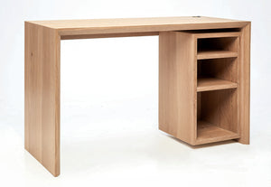 image of white oak office desk. Has open storage with three shelves. Minimalist designed office desk with mitered edges and beveled front edge. There is a brass grommet for electrical cord management.. 