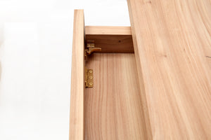 Detailed photo on the inside of the floating drawer on the minimalist cascade desk. Brass hinge hardware connecting the drawer front to the base can be seen. Brass latch can be seen. Latch allows the front drawer face to drop down so computer keyboard located inside the drawer can be used.